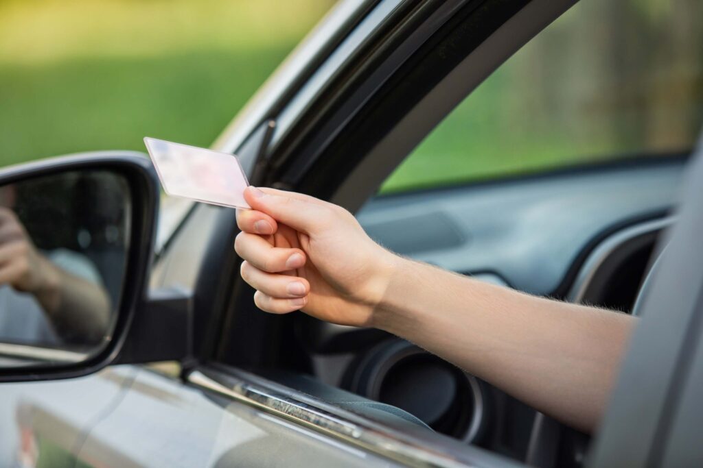 Close up of the person's hand on the car window with the driver's license as it is shown to the police officer for control