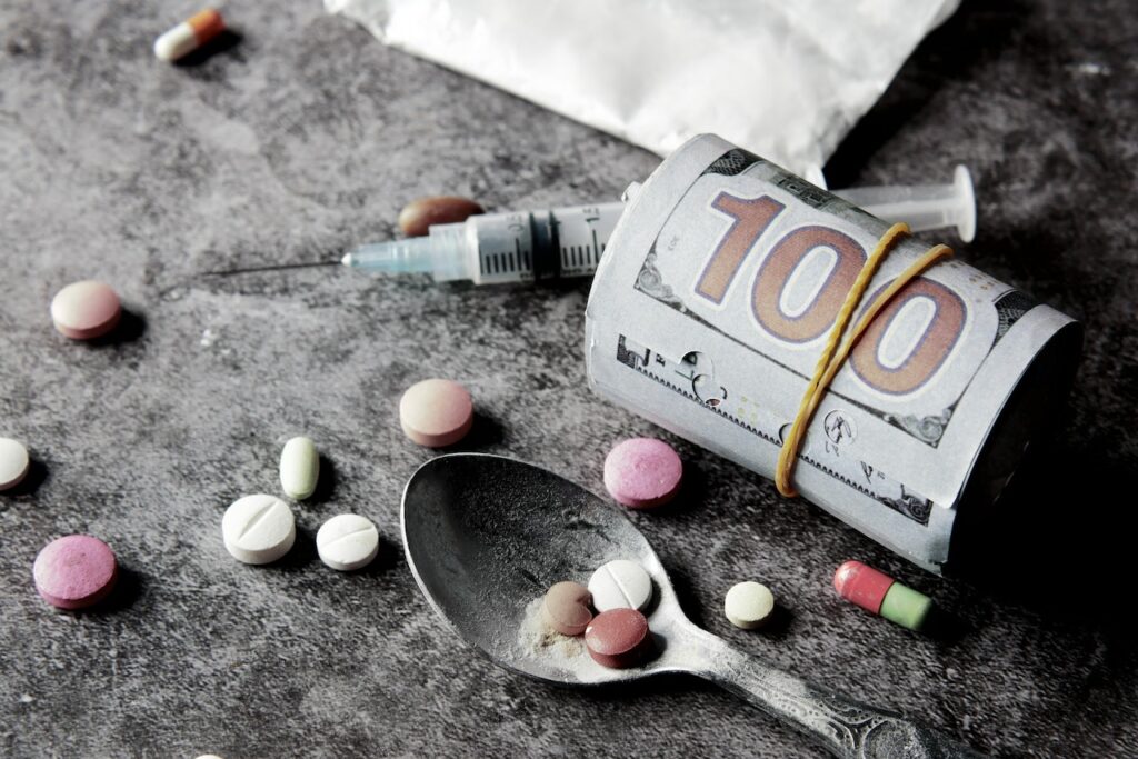 Pills, a spoon, a syringe and money laying in the ground