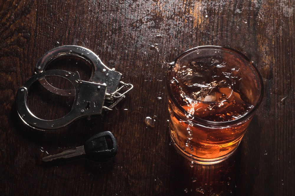 A Glass Of Liquor, Handcuffs And Car Keys On A Table
