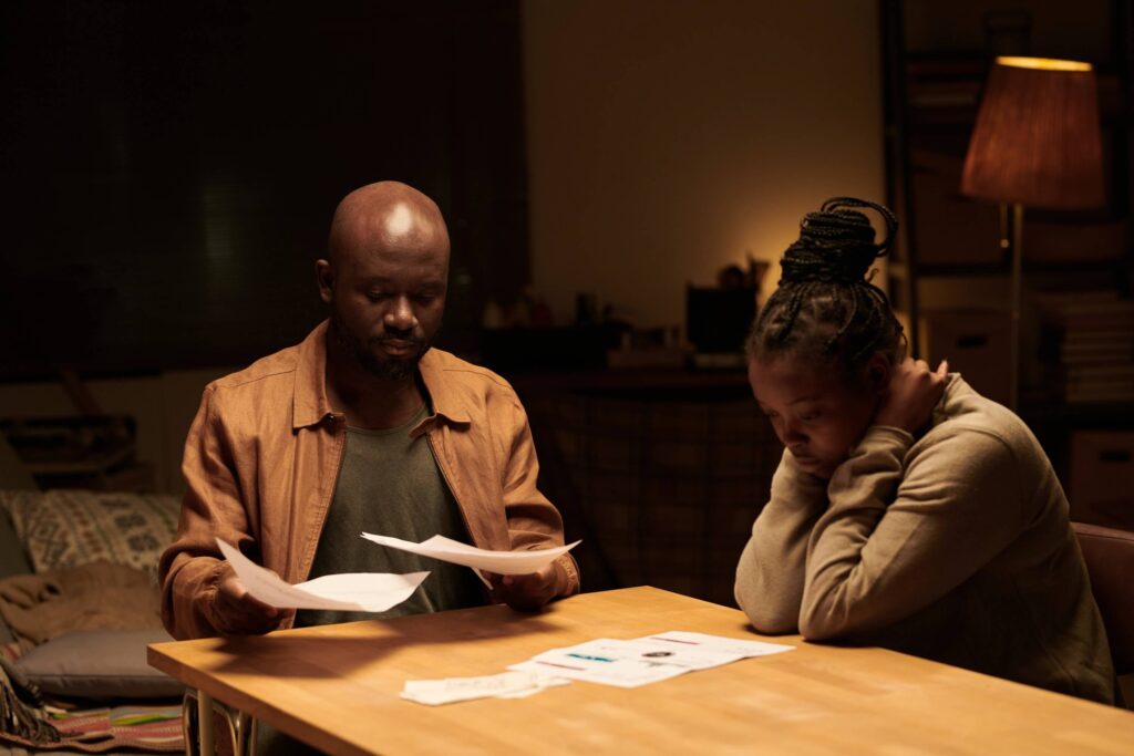 Troubled young woman and her husband looking through unpaid financial bills